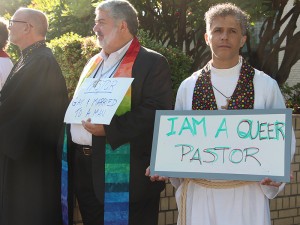 Священник с плакатом "Я - квир-пастор"