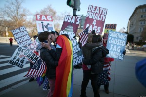 Однополые пары целуются на фоне гомофобных плакатов